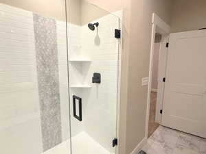 Bathroom featuring light marble finish floors and a stall shower