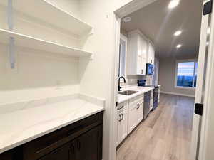 Kitchen featuring light wood-type flooring, black appliances, recessed lighting, light stone countertops, and white cabinets