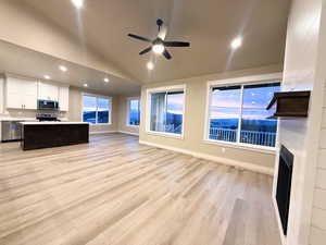 Unfurnished living room with light wood-type flooring, ceiling fan, a fireplace, recessed lighting, and high vaulted ceiling