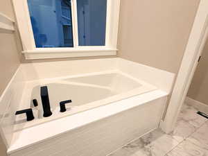 Bathroom with a garden tub and light marble finish floors
