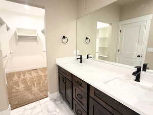 Bathroom with a spacious closet, double vanity, and light marble finish flooring