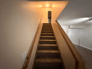 Staircase with wood finished floors and baseboards