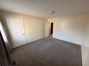 Unfurnished bedroom with carpet and a textured ceiling