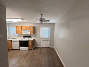 Kitchen featuring white appliances, light countertops, dark wood-style flooring, a textured ceiling, and plenty of natural light