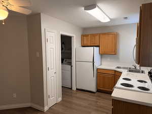 Kitchen with white appliances, light countertops, washer / clothes dryer, a textured ceiling, and dark wood finished floors
