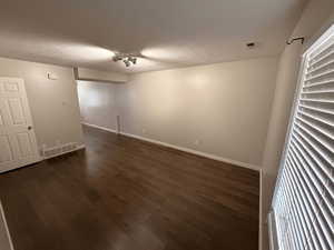 Unfurnished room featuring dark wood-type flooring and a textured ceiling