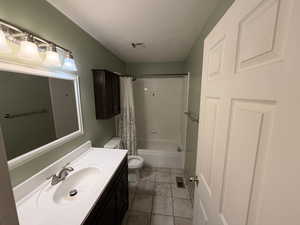 Full bath with shower / bathtub combination with curtain, vanity, a textured ceiling, and dark tile patterned floors