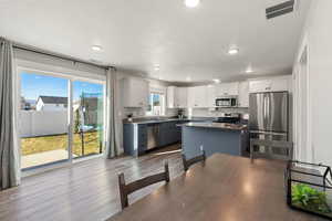 Kitchen featuring white cabinets, appliances with stainless steel finishes, gray cabinetry, wood finished floors, and recessed lighting