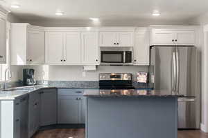 Kitchen featuring gray cabinetry, appliances with stainless steel finishes, and white cabinets