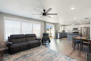 Living area with light wood-style flooring, ceiling fan, and recessed lighting