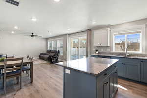 Kitchen with gray cabinets, dark stone countertops, light wood finished floors, a center island, and recessed lighting