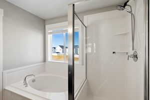 Primary suite bath featuring a stall shower and a bath