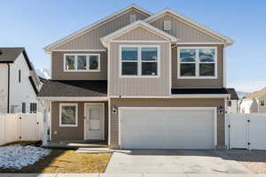 View of front of property featuring a gate, roof with shingles, a garage, and driveway