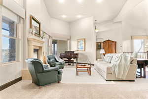 Carpeted living area with a high ceiling, a premium fireplace, and recessed lighting