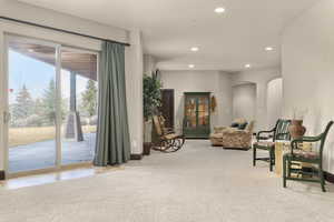 Sitting room with arched walkways, light colored carpet, and recessed lighting
