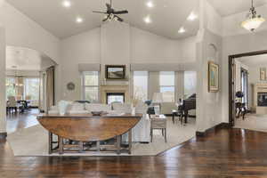 Living area with a glass covered fireplace, dark wood-style floors, arched walkways, lofted ceiling, and recessed lighting