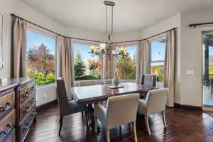 Dining space with dark wood-style floors and a chandelier