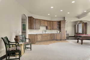 Kitchen featuring arched walkways, billiards, recessed lighting, light colored carpet, and wood finish cabinets
