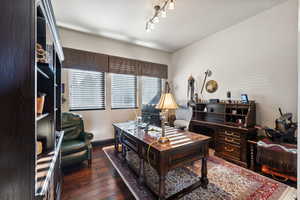 Home office with dark wood-style flooring and baseboards