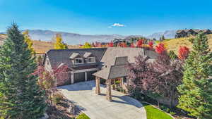 View of front of house featuring stone siding, a porch, driveway, a garage, and a mountain view