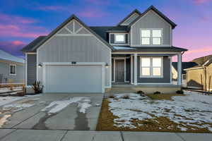 View of front of home with board and batten siding, driveway, a garage, and a porch