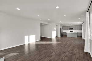 Unfurnished living room featuring recessed lighting and dark wood-type flooring