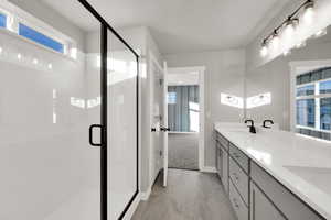 Full bath featuring double vanity and a shower stall