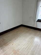 Empty room featuring baseboards and light wood-style flooring