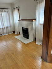 Unfurnished living room featuring light wood-style floors and a brick fireplace