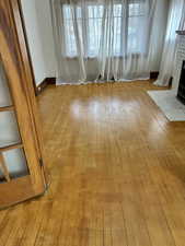 Unfurnished living room featuring light wood finished floors and a brick fireplace