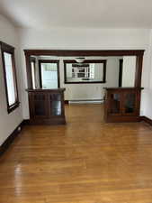 Unfurnished living room featuring hardwood / wood-style floors and baseboard heating