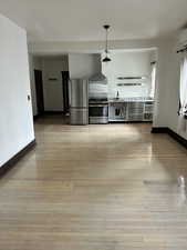 Kitchen with appliances with stainless steel finishes, decorative light fixtures, light wood-style flooring, and light countertops