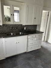 Kitchen with white cabinets, backsplash, and dark stone counters