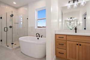 Full bathroom with a stall shower, a freestanding tub, vanity, tile walls, and light tile patterned floors