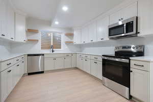 Kitchen featuring open shelves, stainless steel appliances, white cabinets, light wood-style floors, and recessed lighting