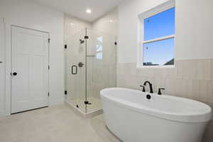 Full bathroom with a stall shower, a freestanding tub, tile walls, wainscoting, and recessed lighting