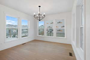 Unfurnished dining area with light wood-style floors, a chandelier, and a mountain view