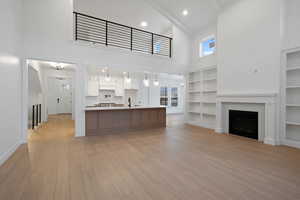 Unfurnished living room with high vaulted ceiling, a fireplace, light wood-type flooring, recessed lighting, and beamed ceiling