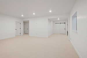 Spare room with a barn door, light carpet, and recessed lighting
