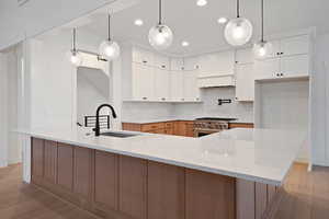 Kitchen with light wood-type flooring, tasteful backsplash, light stone counters, and recessed lighting