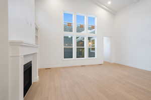 Unfurnished living room featuring a fireplace, light wood finished floors, high vaulted ceiling, and beamed ceiling