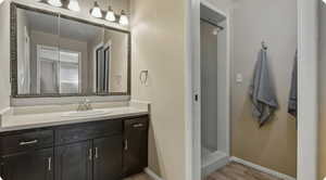 Full bath with vanity, a stall shower, and light wood-type flooring