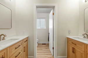 Full bathroom with two vanities and light wood-type flooring