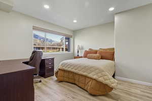 Bedroom featuring light wood-type flooring, a mountain view, a desk, and recessed lighting