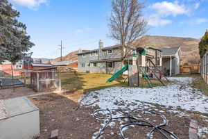 Fenced backyard with a playground, an outbuilding, and a mountain view
