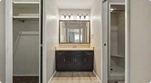 Full bathroom featuring a spacious closet, vanity, a stall shower, and light wood-type flooring