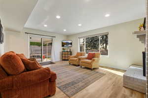 Living room featuring light wood-type flooring, recessed lighting, and a fireplace