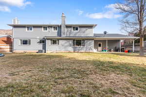 Back of house featuring a fenced backyard, a chimney, brick siding, and a patio area