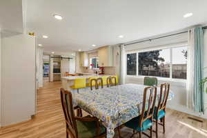 Dining area with a barn door, light wood-style floors, and recessed lighting