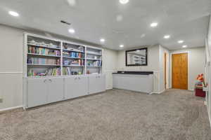 Unfurnished room with light carpet, recessed lighting, and bar with sink